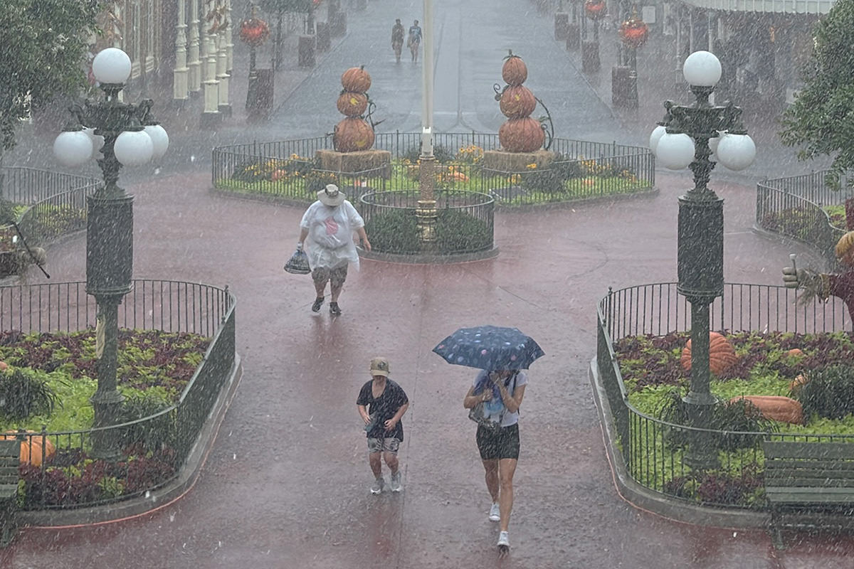 People running through a massive downpour in an empty Magic Kingdom's Main Street USA.